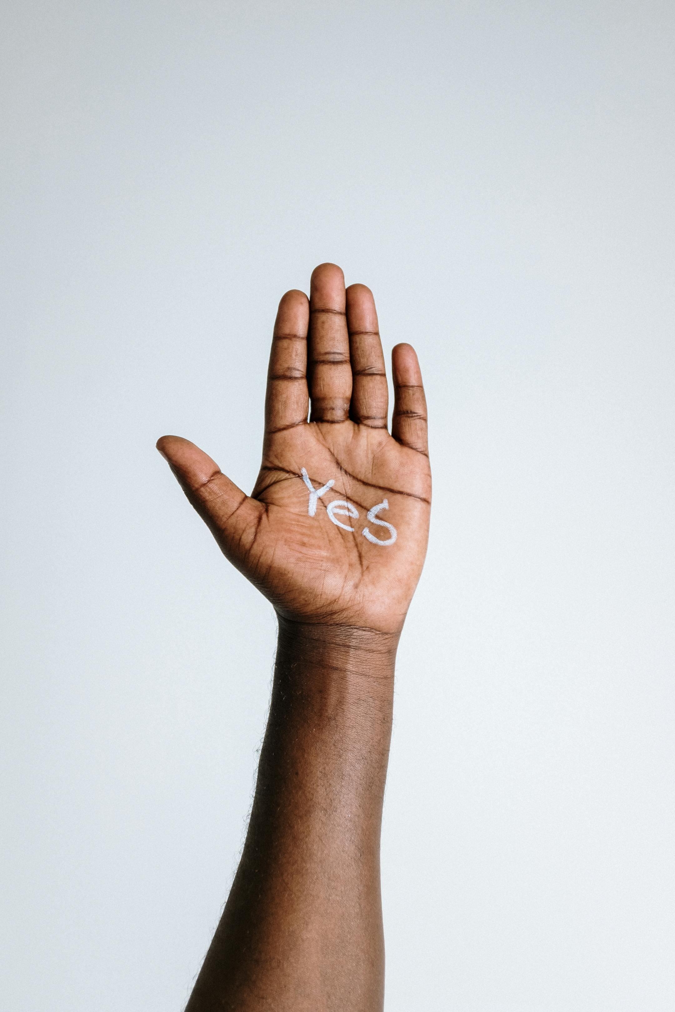 A close-up of an open hand with the word 'Yes' written on the palm, conveying affirmative gesture.