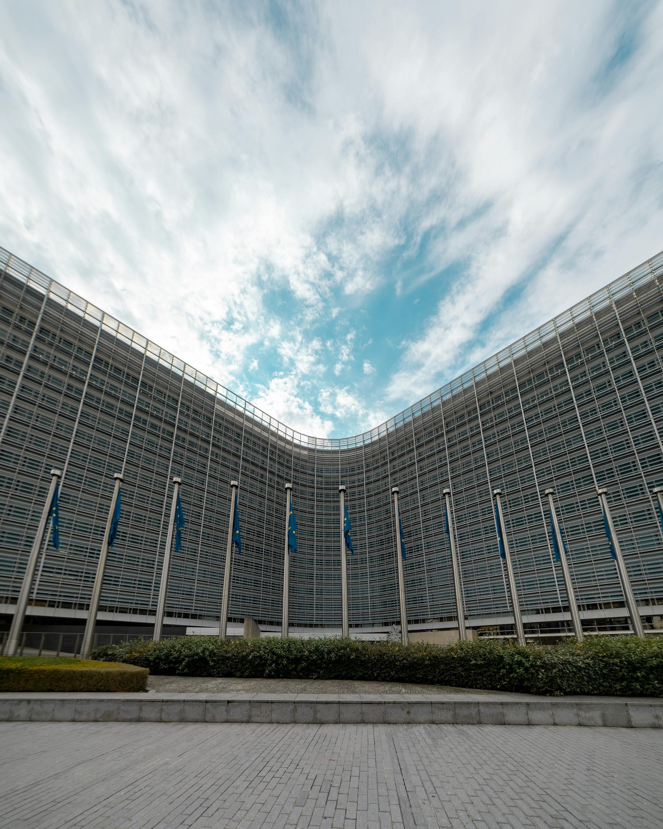 Low angle view of the European Commission building with flags and blue sky in Brussels.