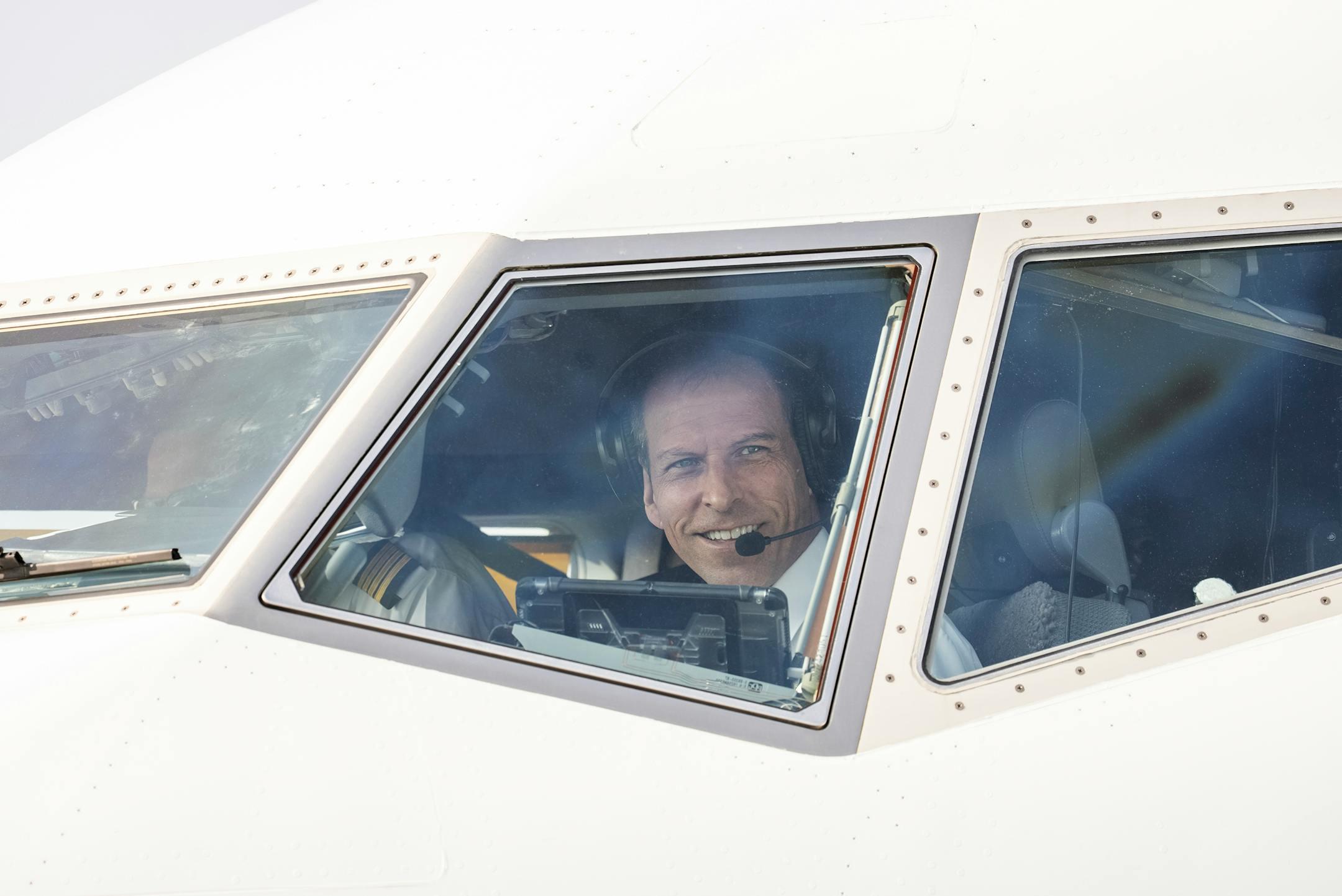 Smiling pilot in airplane cockpit, showcasing aviation professionalism.