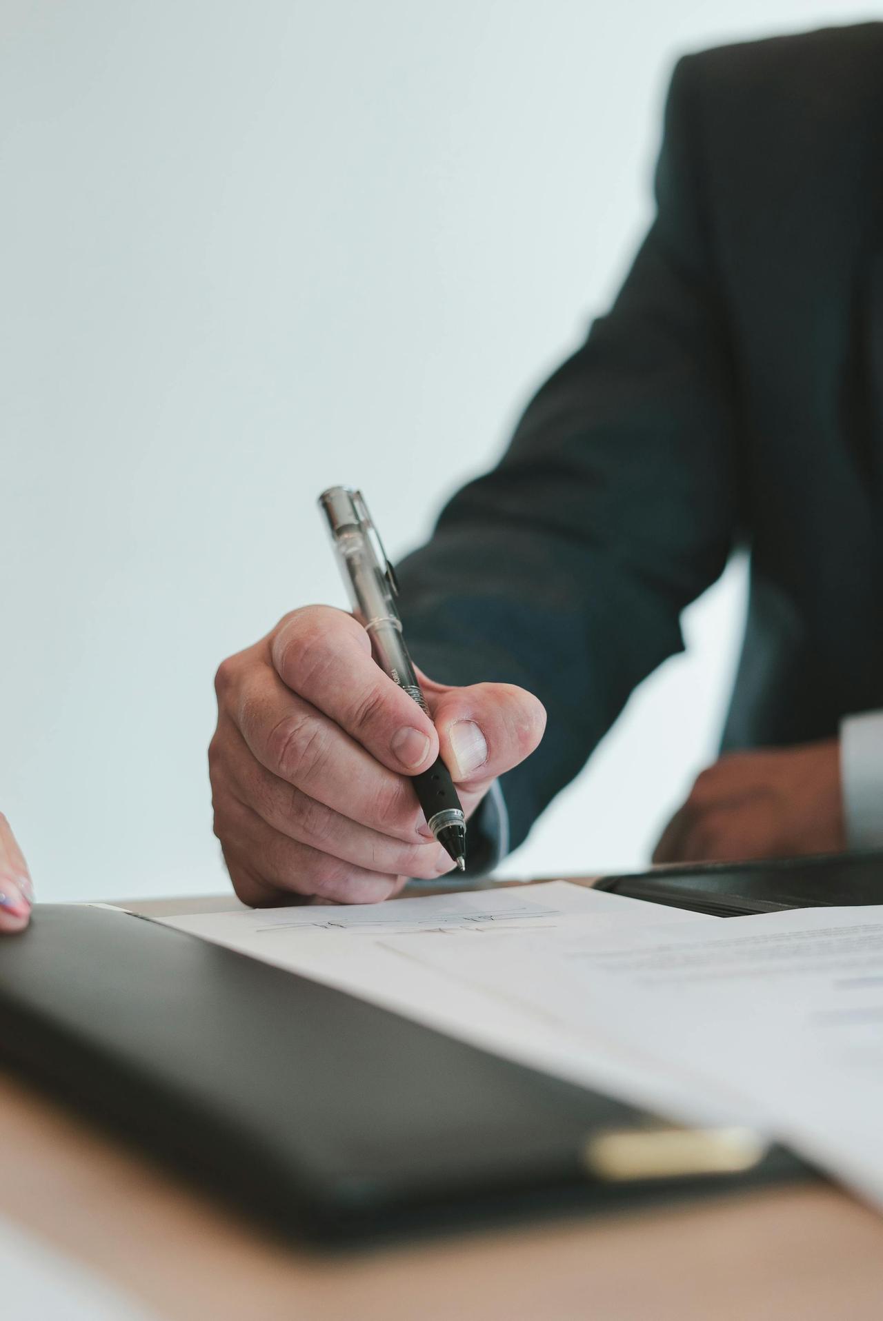 A businessman in a suit signing a contract in an office setting, emphasizing professional context.