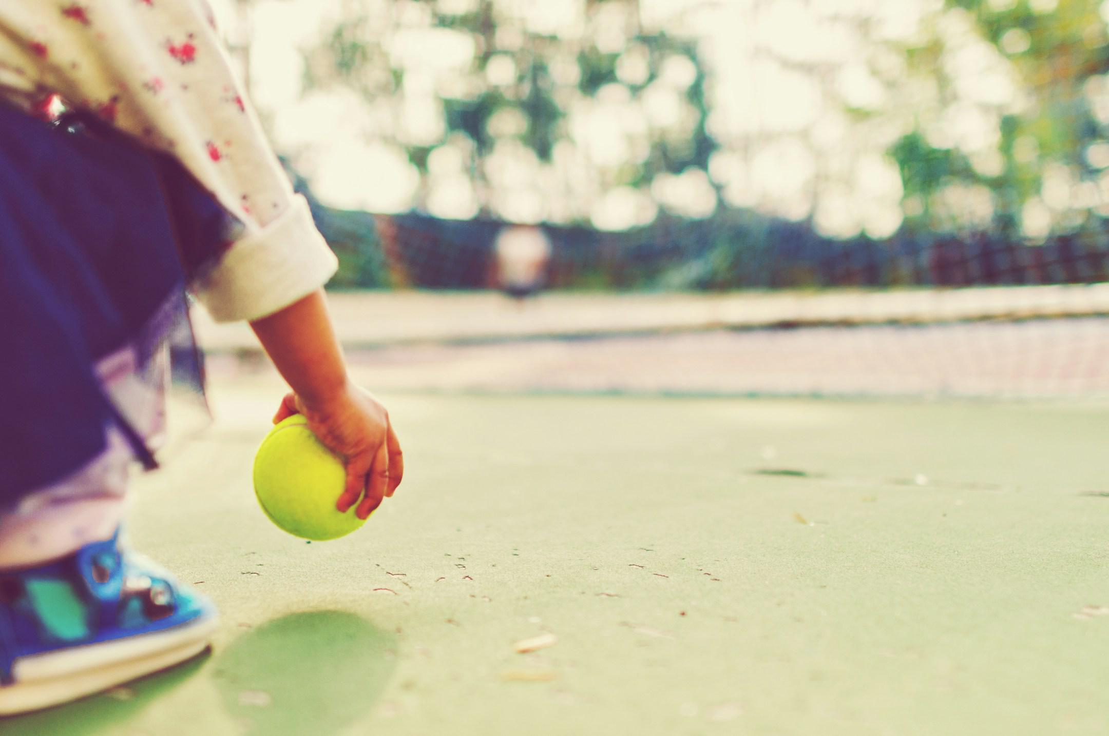A toddler holding a tennis ball in a play ground