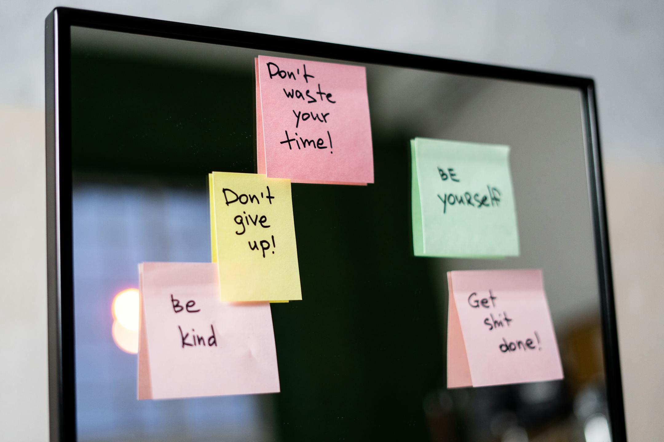 Colorful sticky notes with motivational messages on a mirror reflecting positivity.