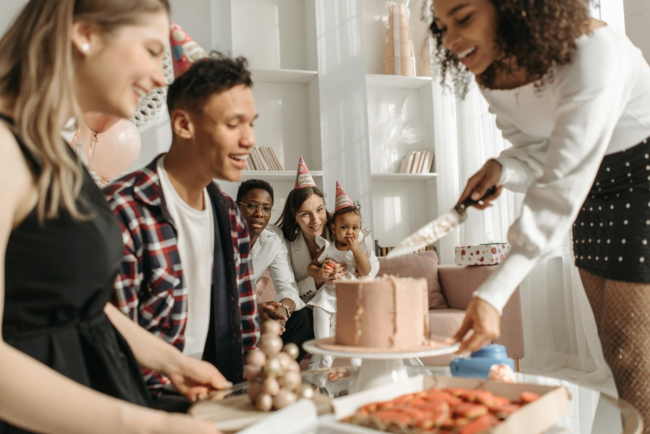 A group of friends enjoying a lively birthday party with cake and smiles in a cozy indoor setting.