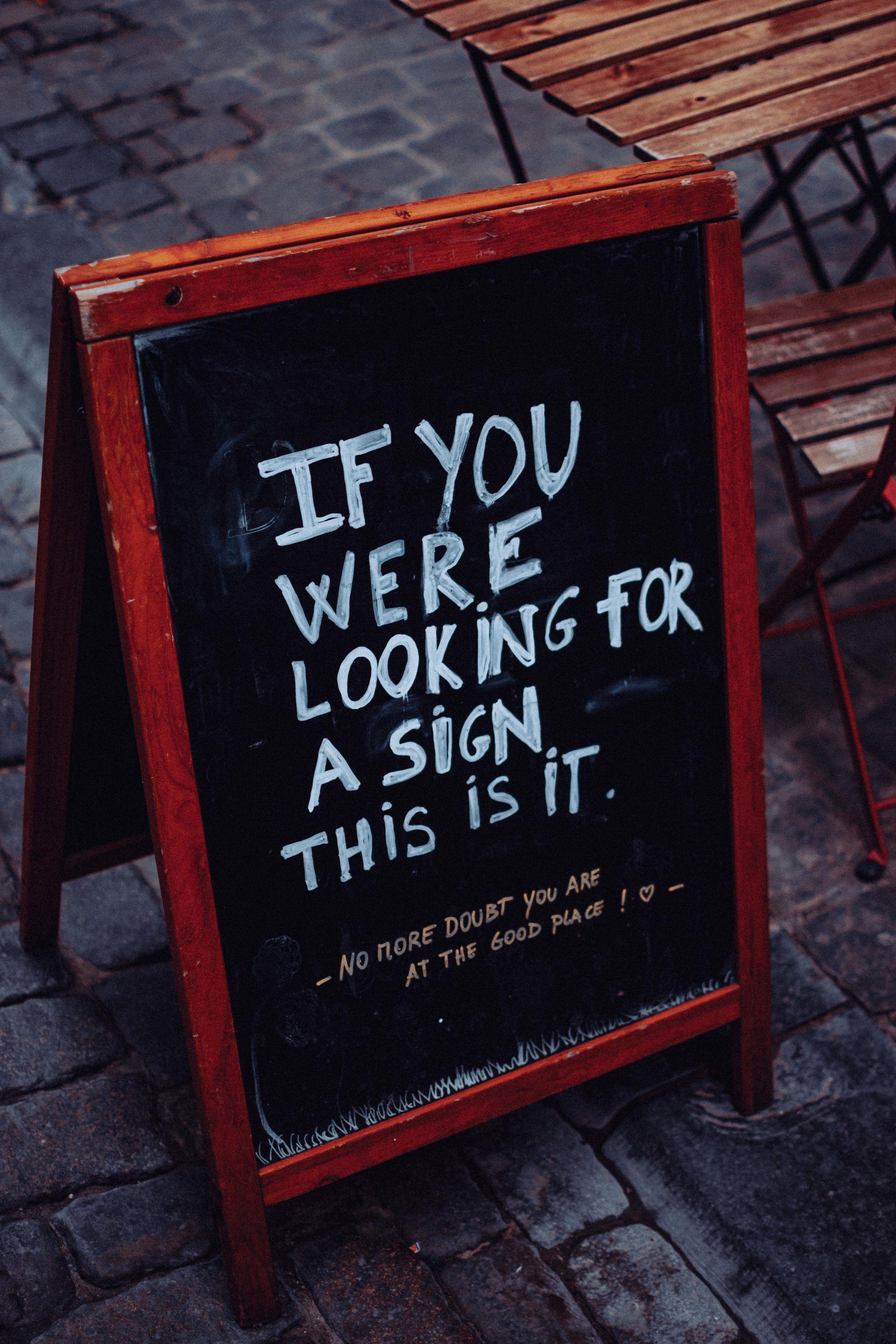 A motivational quote displayed on a chalkboard outside a cozy café.