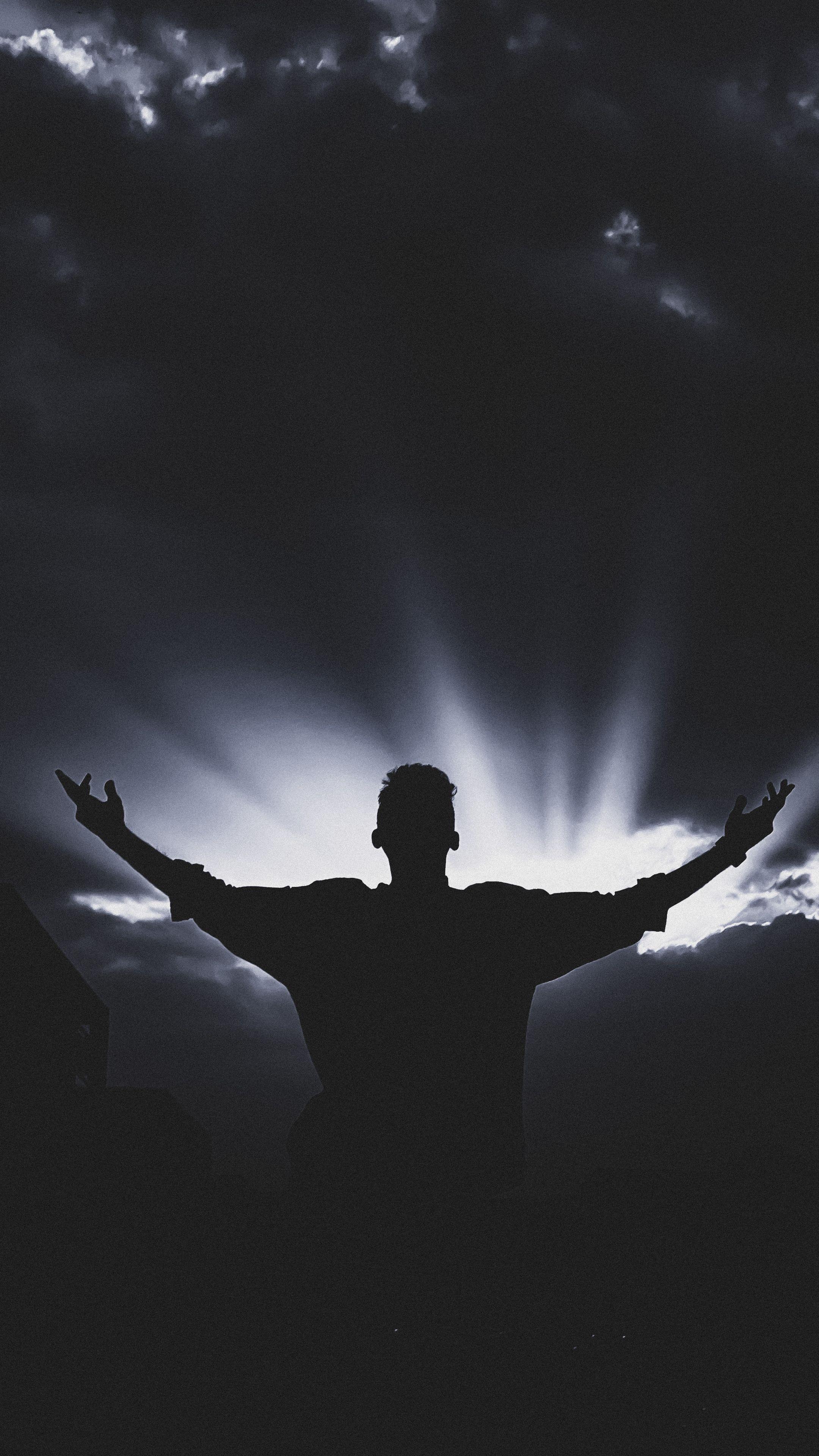 Silhouette of a man with open arms against a dramatic sunset, creating a powerful visual impact.