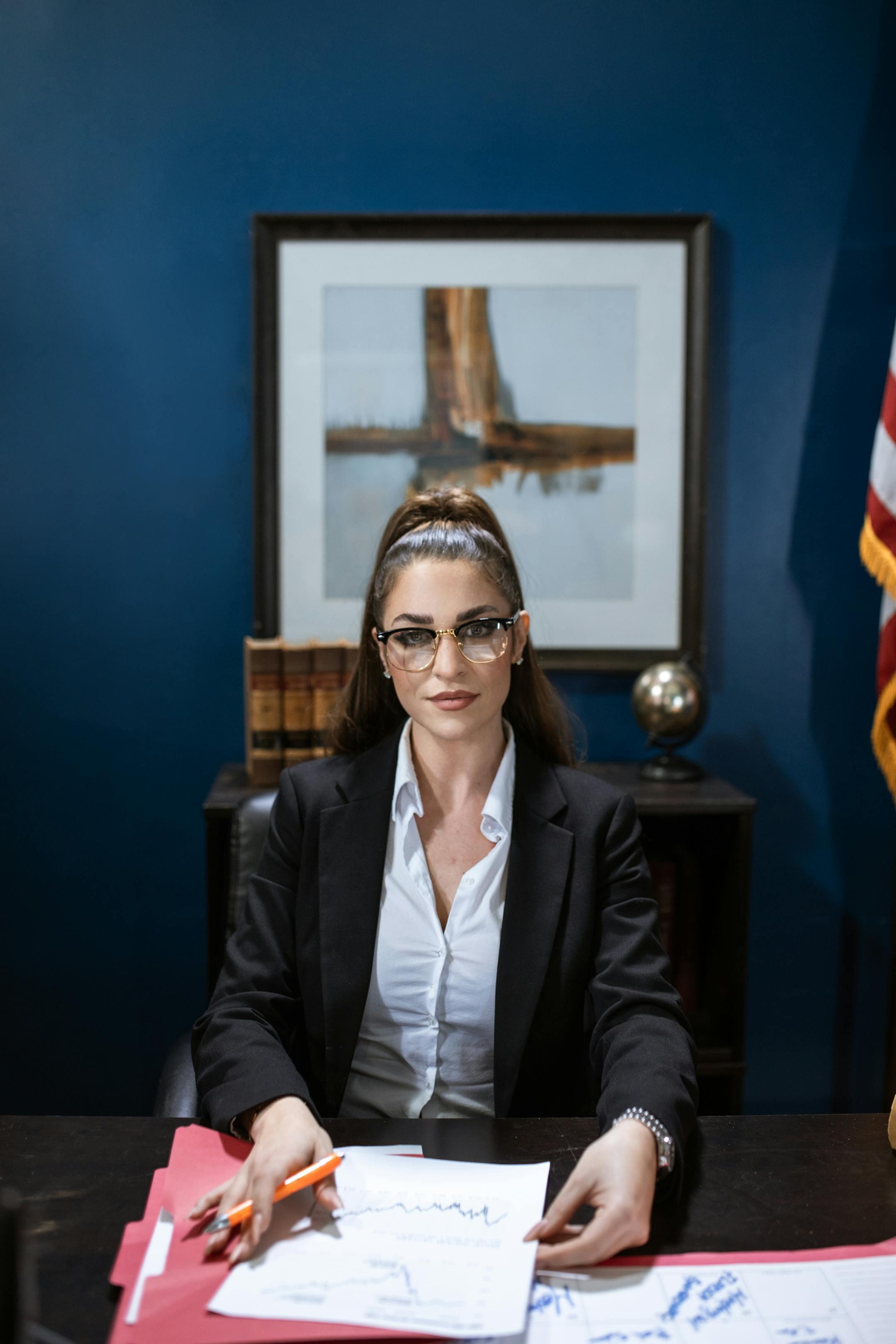 Businesswoman wearing a black blazer working at a desk with papers and charts.