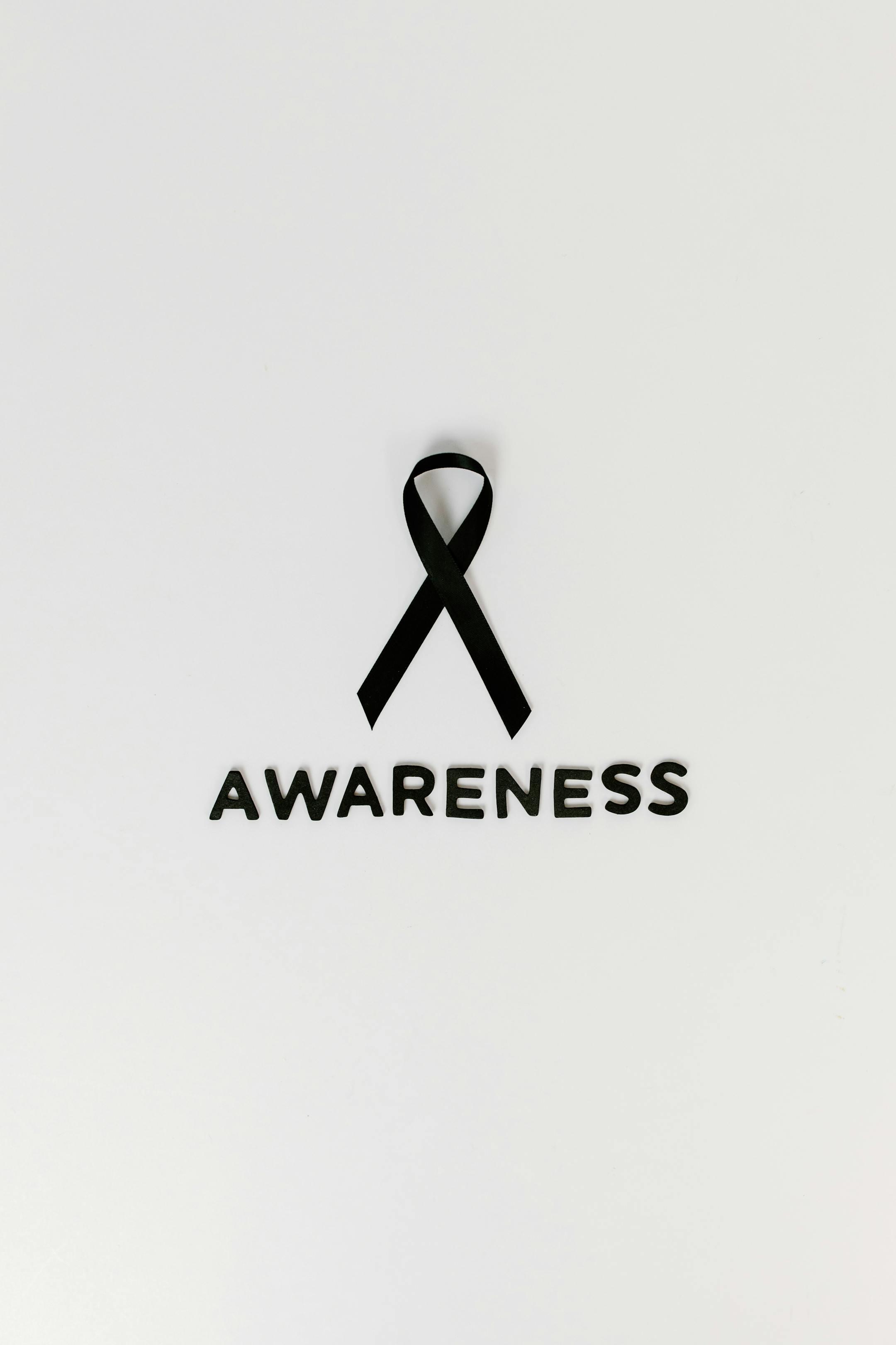 Minimalist image of a black ribbon symbolizing cancer awareness with text.