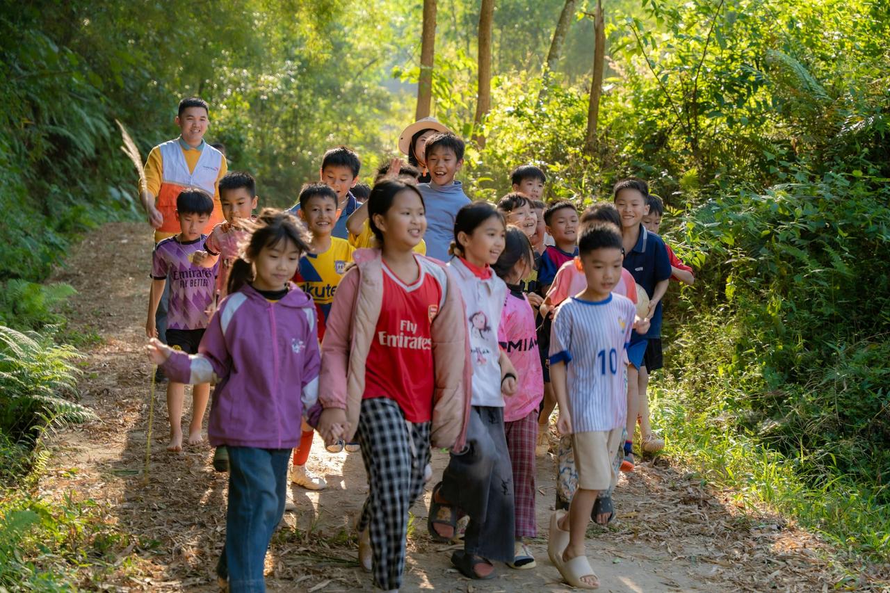 Joyful group of children walking on a sunny forest path enjoying nature.