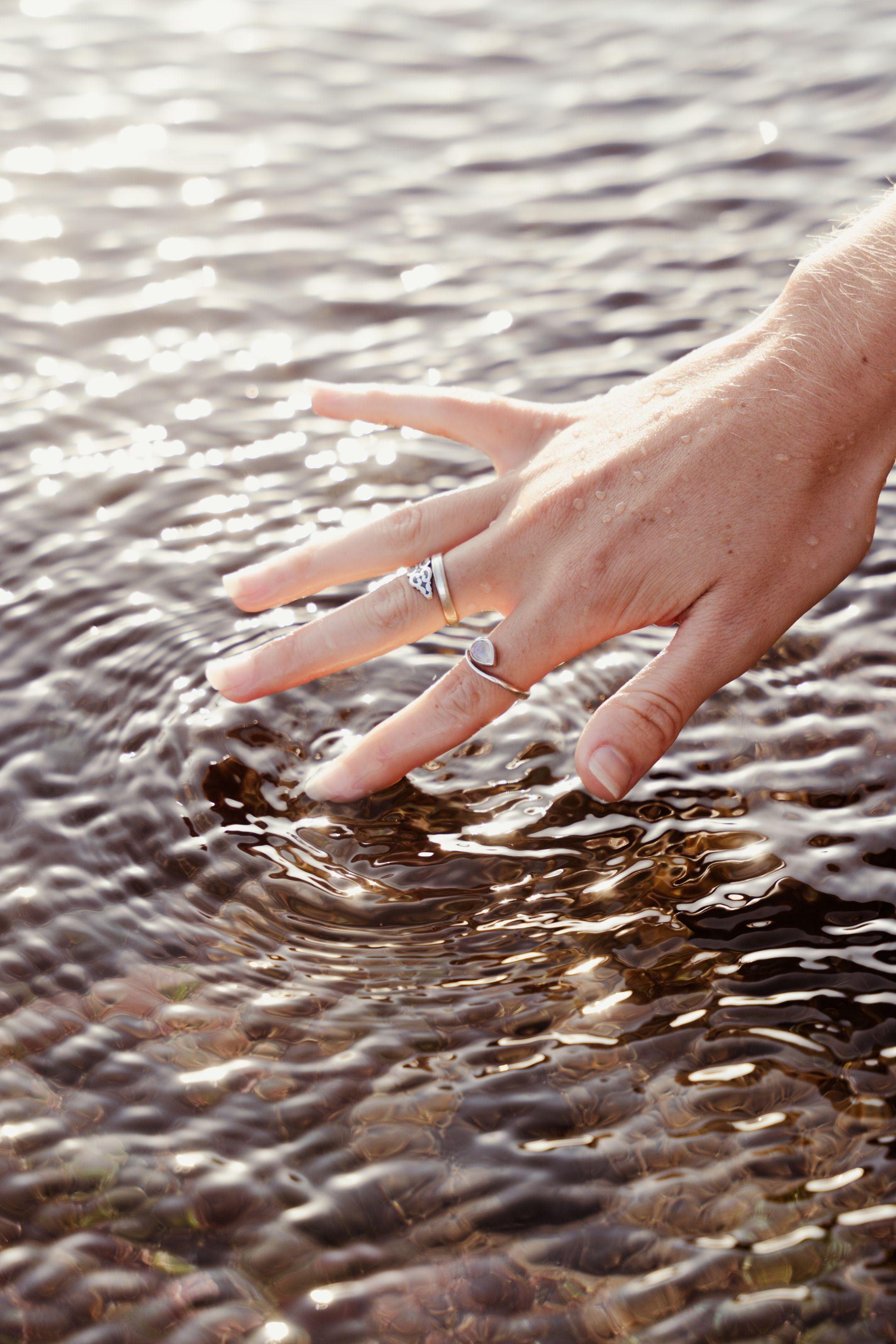 A delicate touch of a hand creating gentle ripples on water surface in Bali, Indonesia.