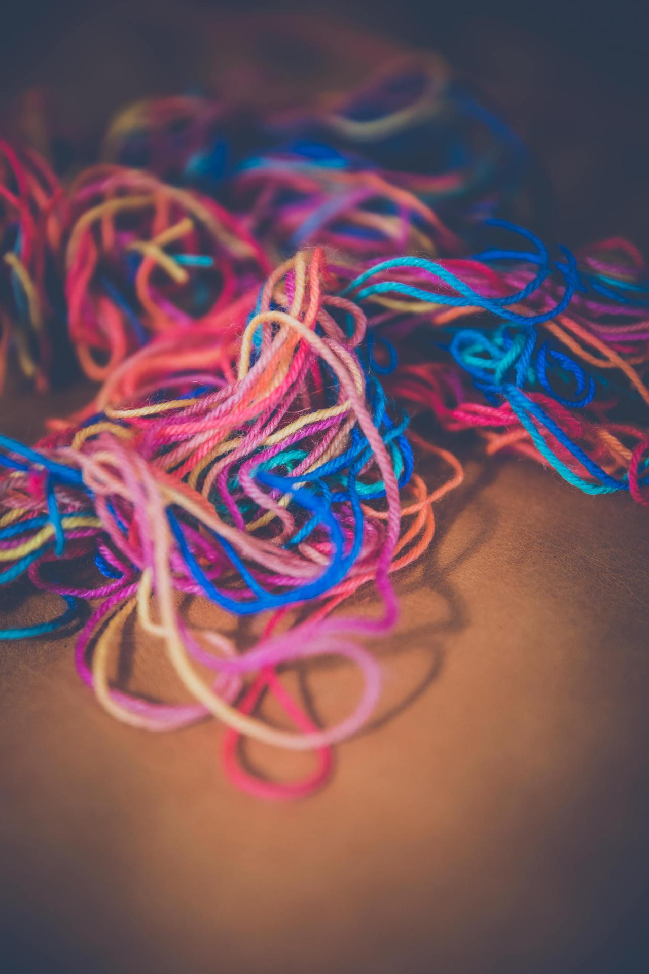 A close-up of colorful yarn strands in various hues on a brown backdrop, perfect for craft and DIY themes.