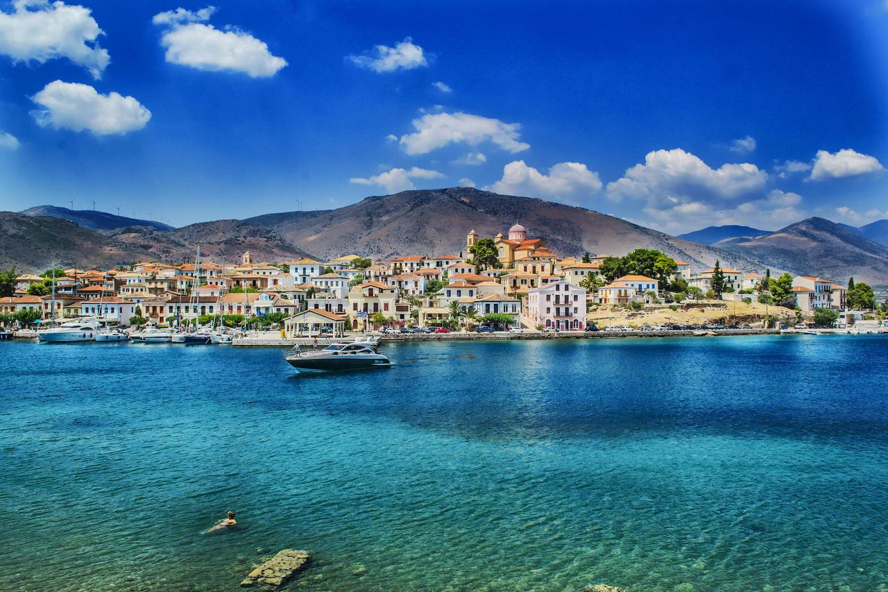 Beautiful coastal view of a charming Greek town against a mountainous backdrop, ideal for travel and vacation imagery.