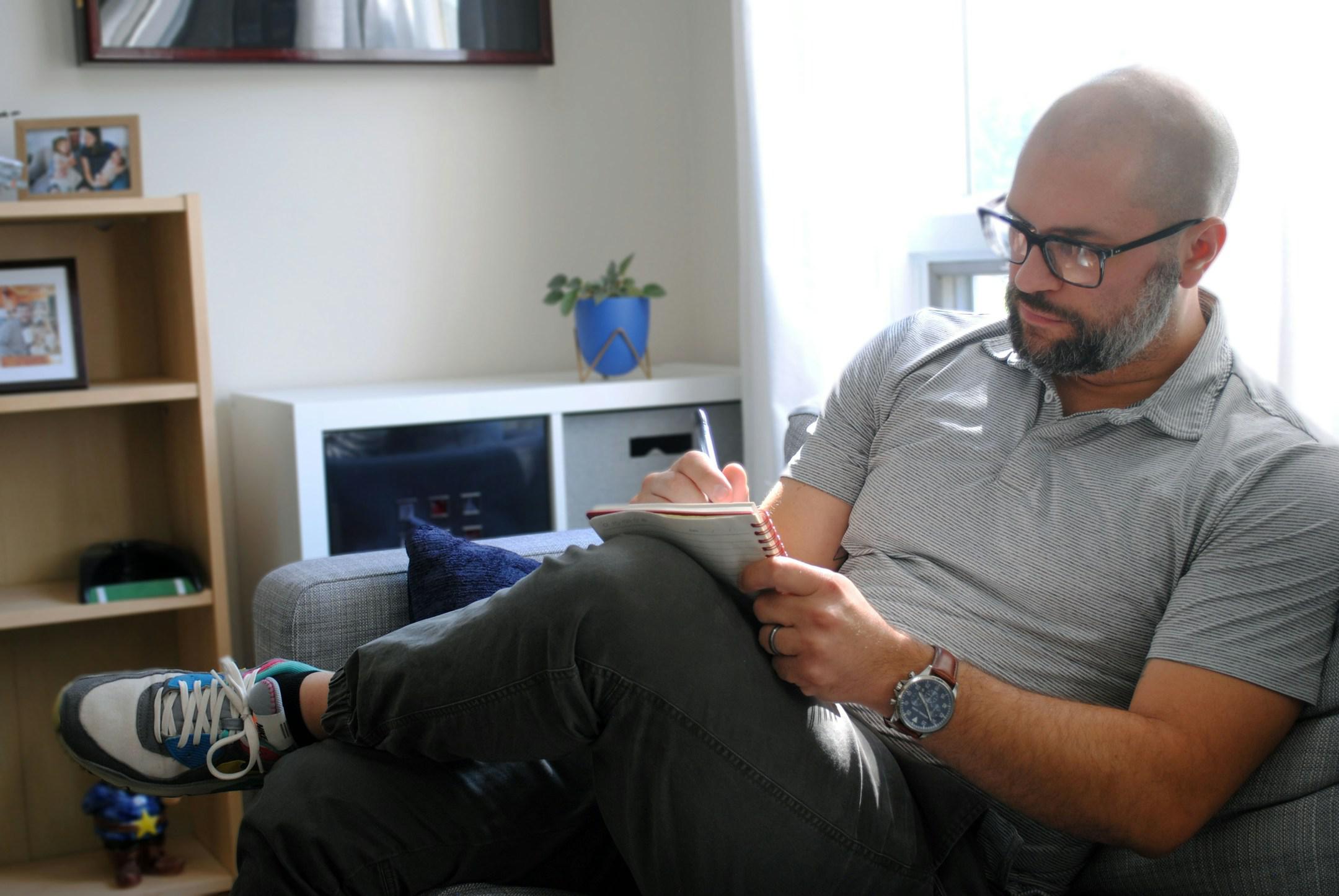 Man taking notes on the couch in office.