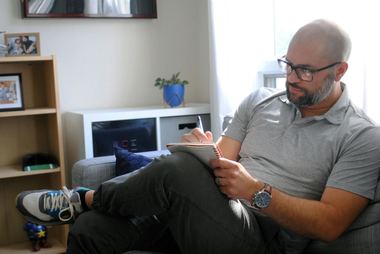 Man taking notes on the couch in office.