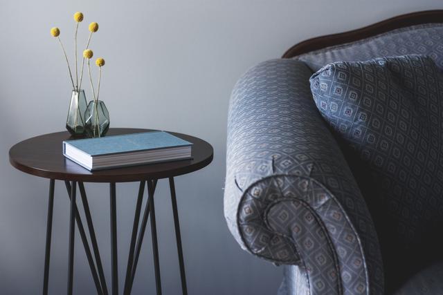 green cover book on round end table beside flower
