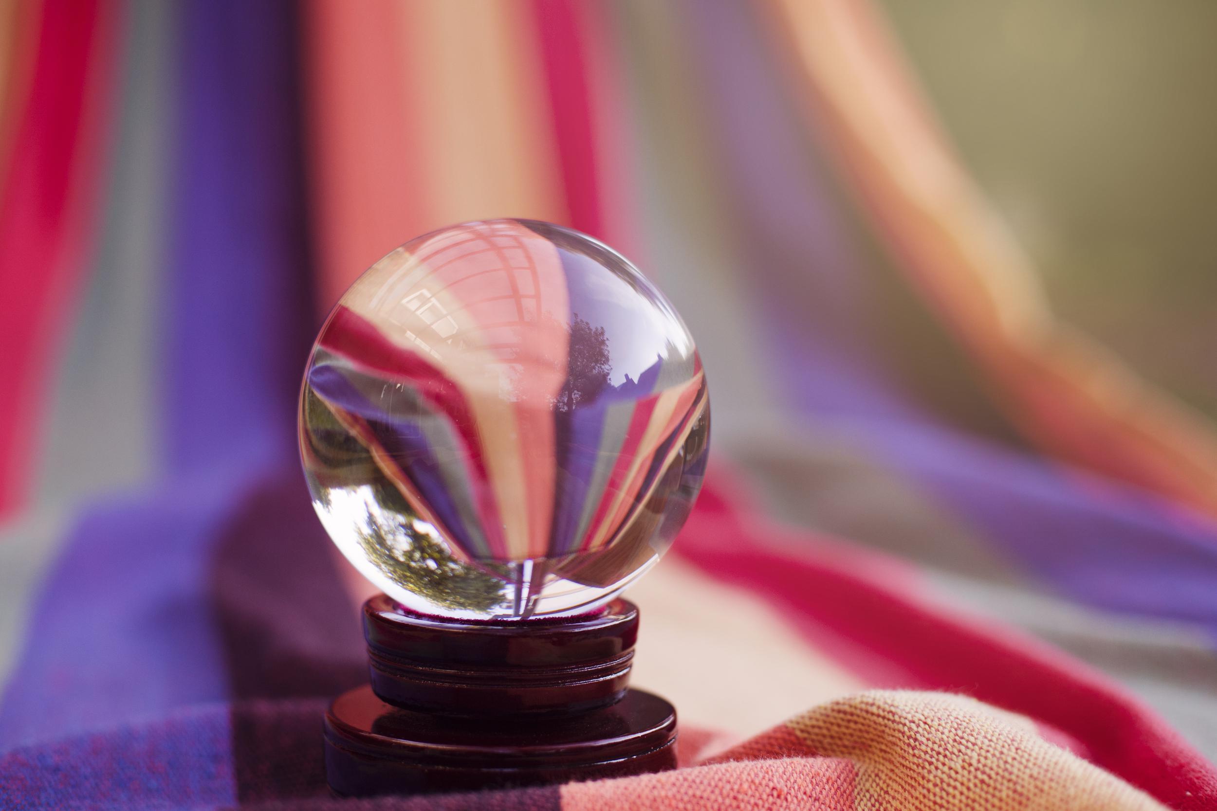 A crystal ball on top of a multi-colored blanket.